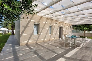 A covered outdoor area with a table and chairs, a tiled floor, and a glass ceiling.