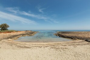 Una spiaggia con acque cristalline, una riva sabbiosa e zone rocciose.