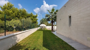 Un patio con césped cuidado, una palmera y un edificio de fachada de ladrillo.