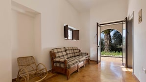 Una habitació amb una cadira de balancí de fusta, un sofà escocès i un petit armari.