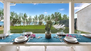 An outdoor dining area with a view of the sea, white tables, and chairs. - Villa Hoara (Brindisi)
