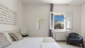 A bedroom with a bed, a chair, a window with a view, and a radiator. - Villa Hoara (Brindisi)