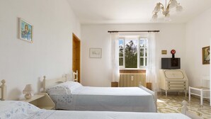 A bedroom with two beds, a radiator, a television, and a window with curtains. - Villa Marù (Taurisano)