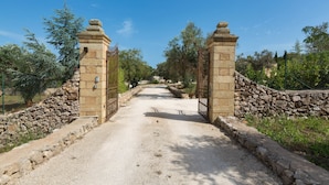 A gravel path leading through a stone gate with a stone wall on one side and a fence on the other. - Villa Satis (Casarano)