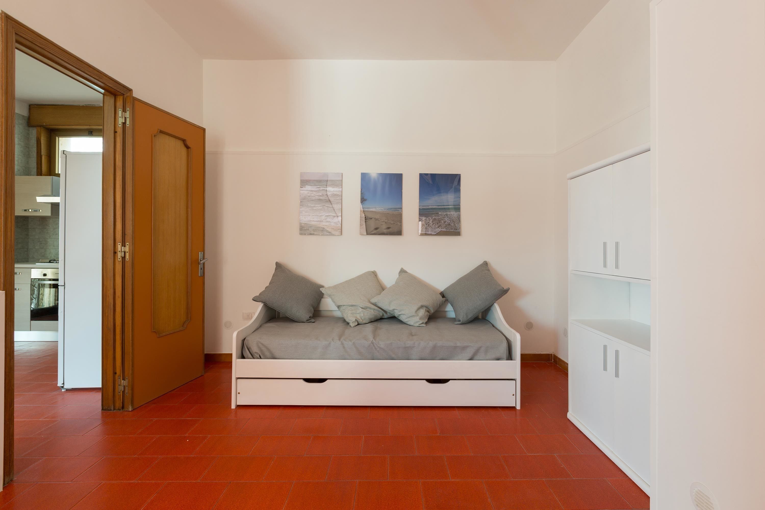 A room with a bed, a wardrobe, and three wall-mounted pictures.