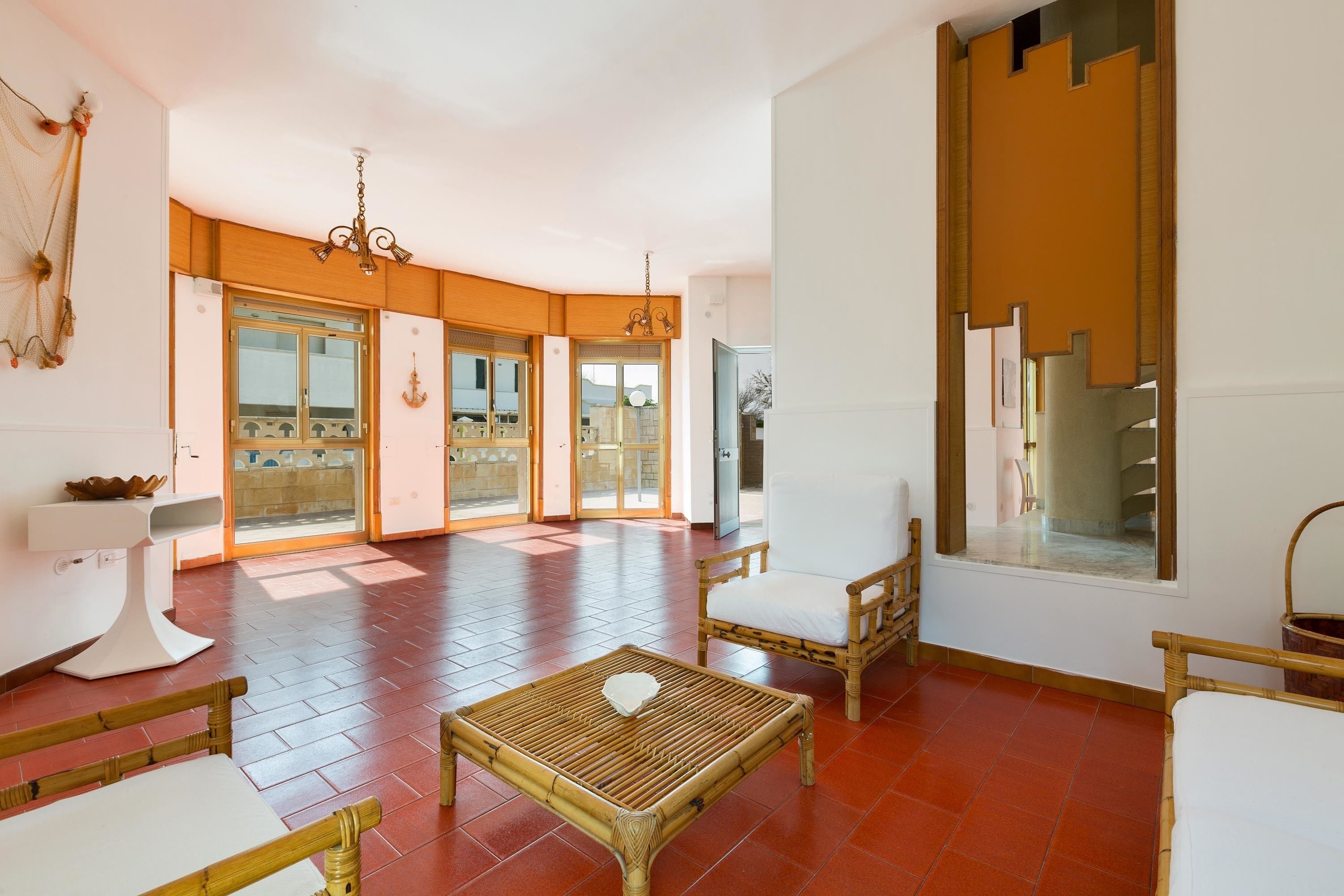 A spacious living area with a large window, a wooden coffee table, and a wicker chair.