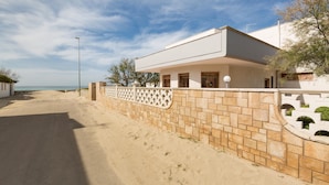 A modern house with a paved driveway and a stone wall. - Villa Scirocco (Porto Cesareo)
