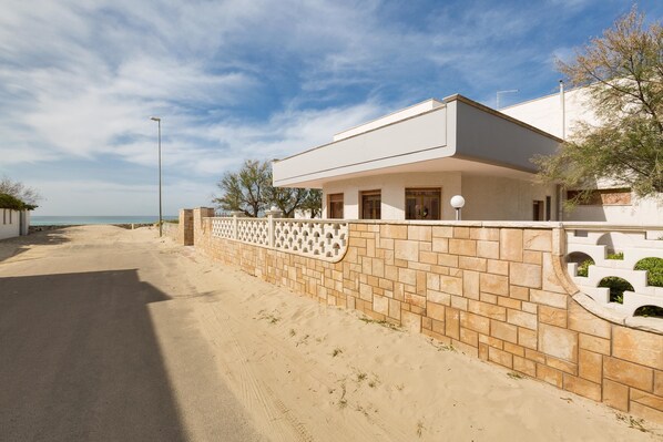 A modern house with a paved driveway and a stone wall. - Villa Scirocco (Porto Cesareo)