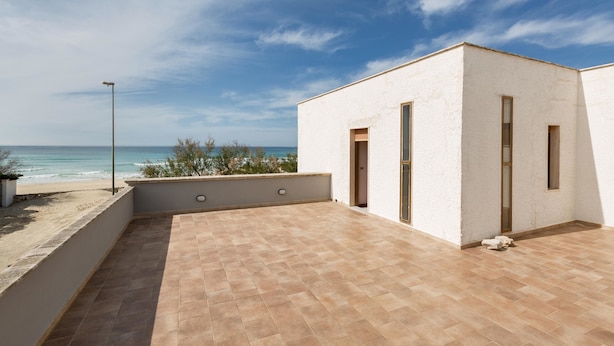 A modern building with a flat roof patio overlooking the sea. - Villa Scirocco (Porto Cesareo)
