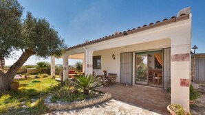 A covered patio with stone flooring, outdoor furniture, and potted plants. - Villetta Baron Beach (Porto Cesareo)
