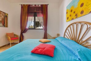 A bedroom with a bed, a chair, a window with curtains, and a painting on the wall. - Villetta Baron Beach (Porto Cesareo)