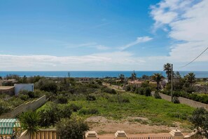 Zona residencial con casas, una palmera y vista al mar.