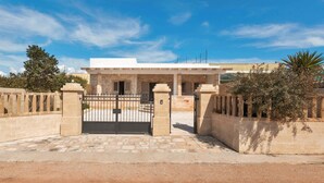 Un bâtiment doté d’une entrée fermée par un portail, de murs en pierre et surplombé d’un ciel d’un bleu éclatant.