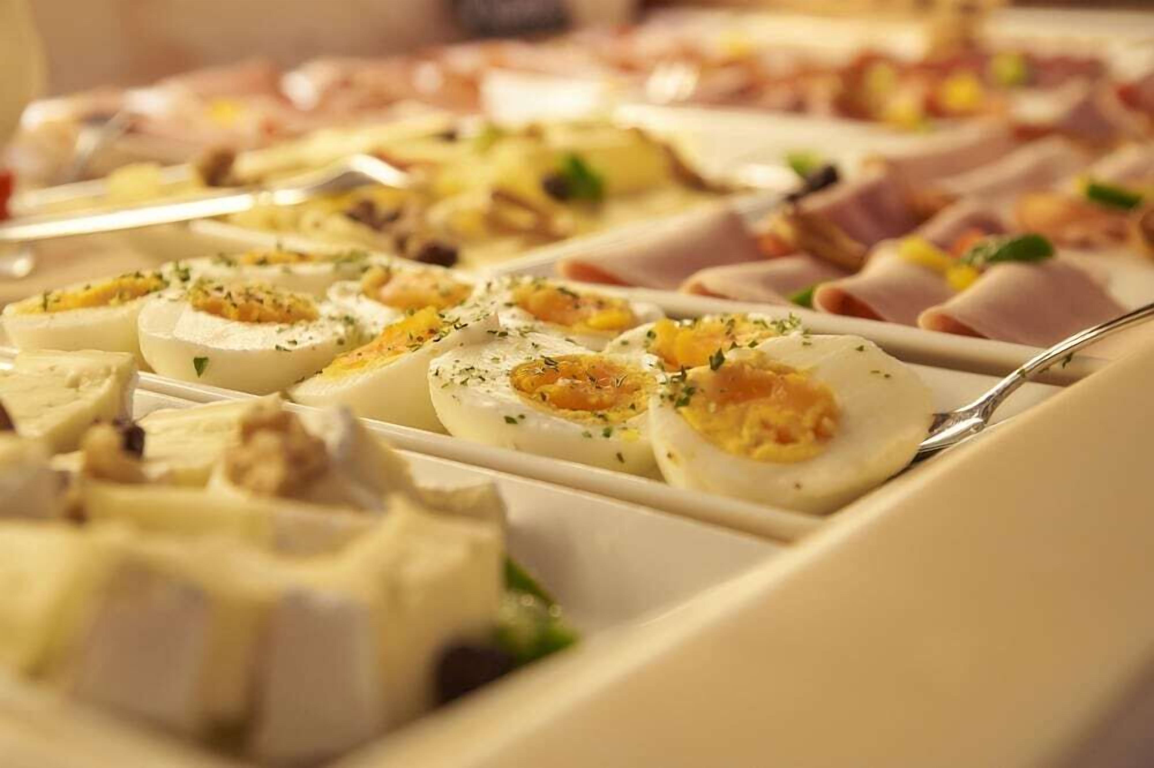Un bufé con diversos alimentos, incluyendo huevos rellenos y carnes.