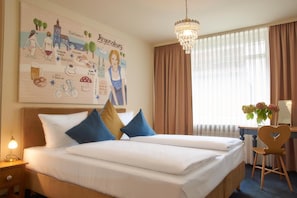 A hotel room with a bed, a desk, a chair, a chandelier, and a wall with a cityscape illustration.
