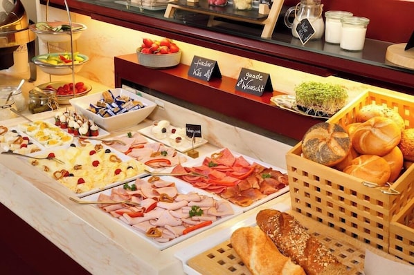 A buffet with various food items including meats, cheeses, and breads.