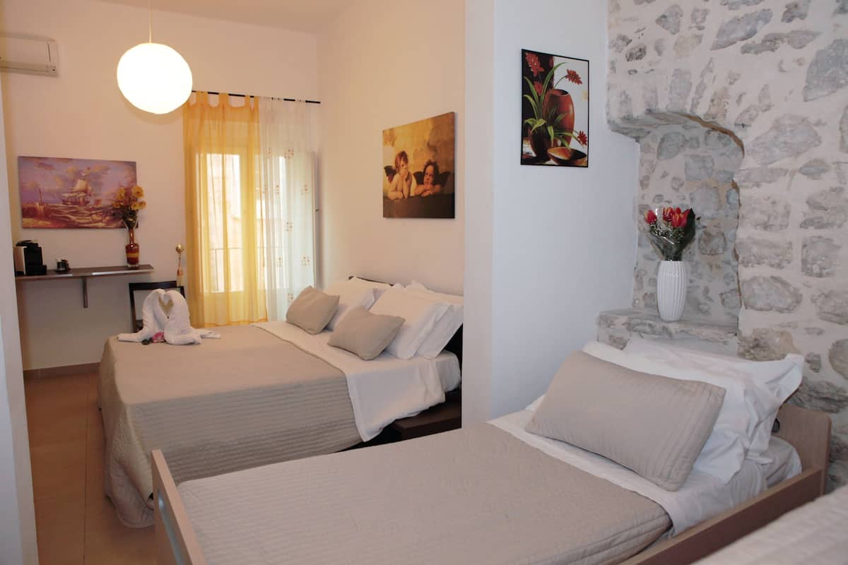 Une chambre d’hôtel avec deux lits, un mur en pierre et un tableau accroché au mur.