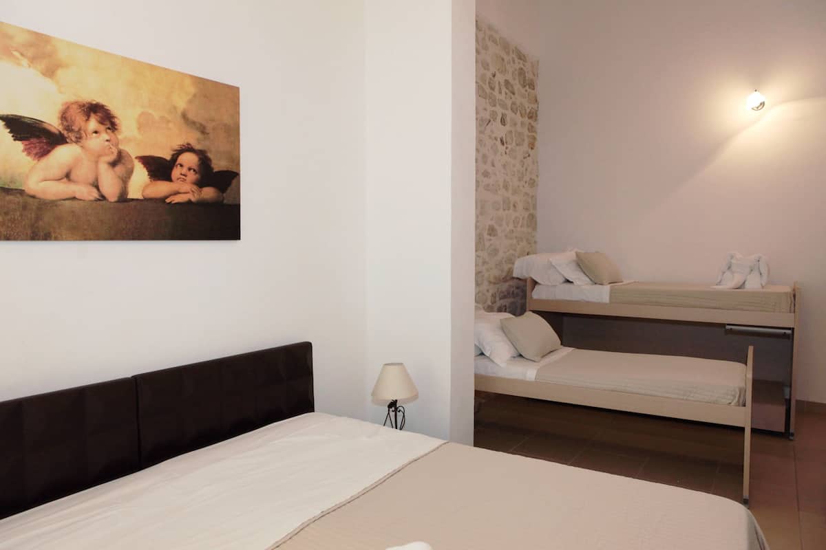 Une chambre à coucher avec un lit, une table de chevet, une lampe et un lit superposé.