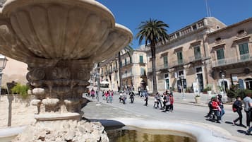 A historic square with a fountain, cobblestone streets, and classical architecture.