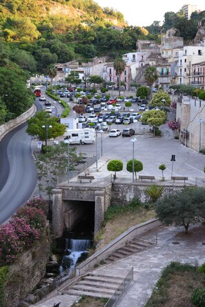 A parking area with cars, a waterfall, and a staircase leading down. - La Corte Di Ibla (Ragusa)