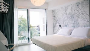 Un dormitorio moderno con una cama grande, vistas a la vegetación a través de un ventanal corredera y una decoración de estilo minimalista.