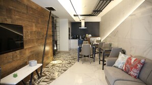 Una sala de estar moderna con televisor, sofá y zona de comedor con sillas y una mesa.