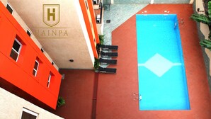 Une piscine sur le toit, avec un élément décoratif aquatique bleu, entourée d’immeubles rouges et beiges.