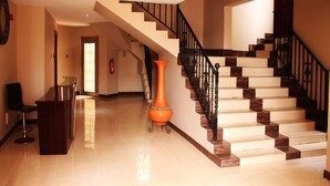 Un hall d’hôtel avec un escalier, un comptoir d’accueil et un extincteur.