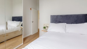 Ein modernes Schlafzimmer mit einem großen Bett, einem Nachttisch mit Lampe und einer kleinen Pflanze.