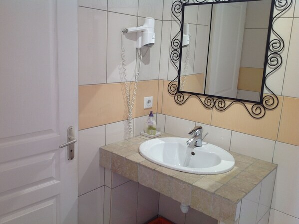 A bathroom with a white sink, a mirror with a decorative frame, and a hairdryer mounted on the wall. - Hotel Le Clos Saint Loup (Bram)