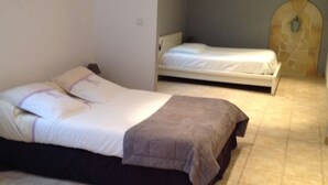 Un dormitorio con dos camas, una pared de piedra y suelo de baldosas.