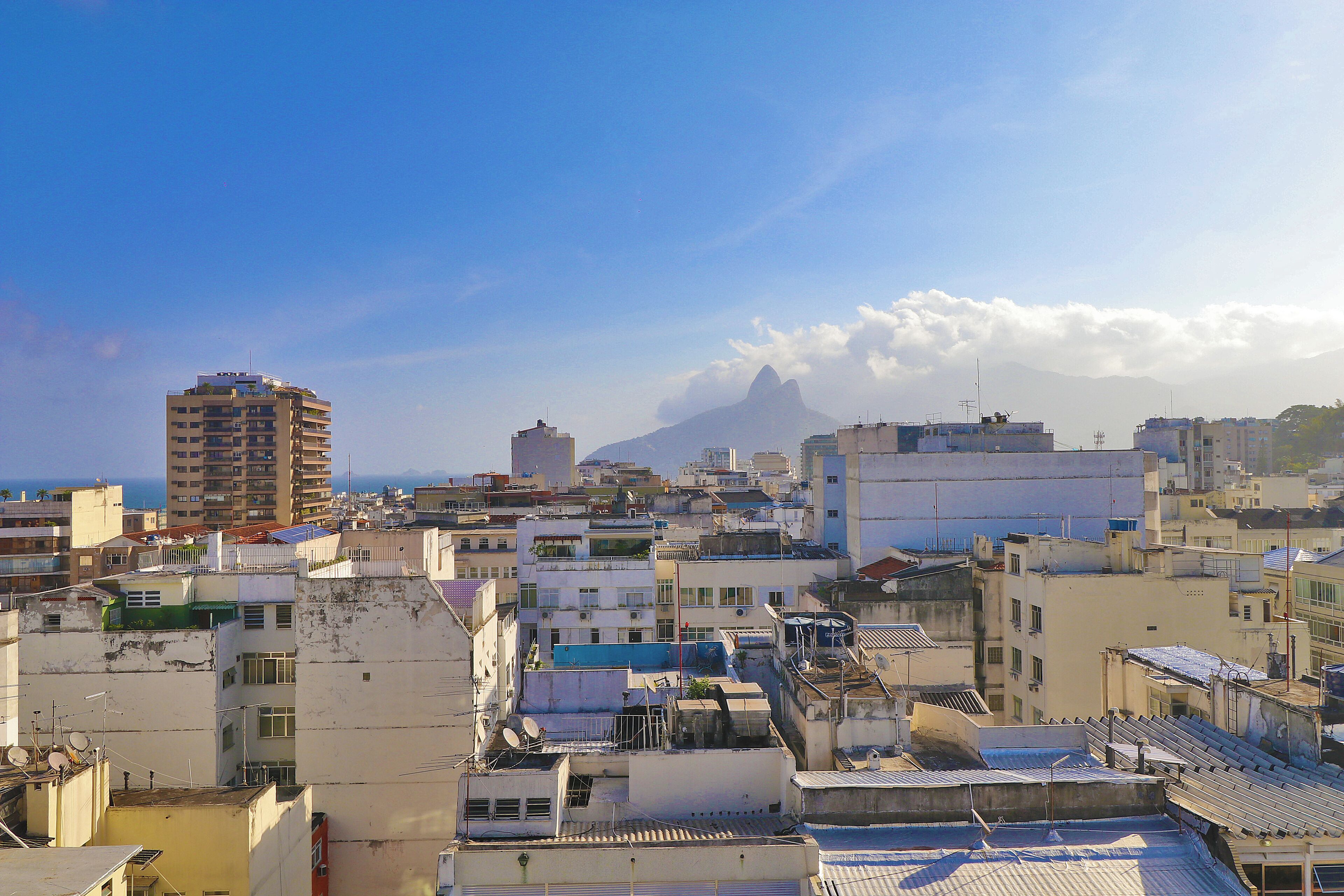 A densely packed urban area with various buildings, including a prominent tall structure and a mountain in the background.