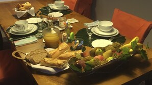 A dining table set with plates, bowls, glasses, and a fruit basket. - Jardins en Ville (Cognac)