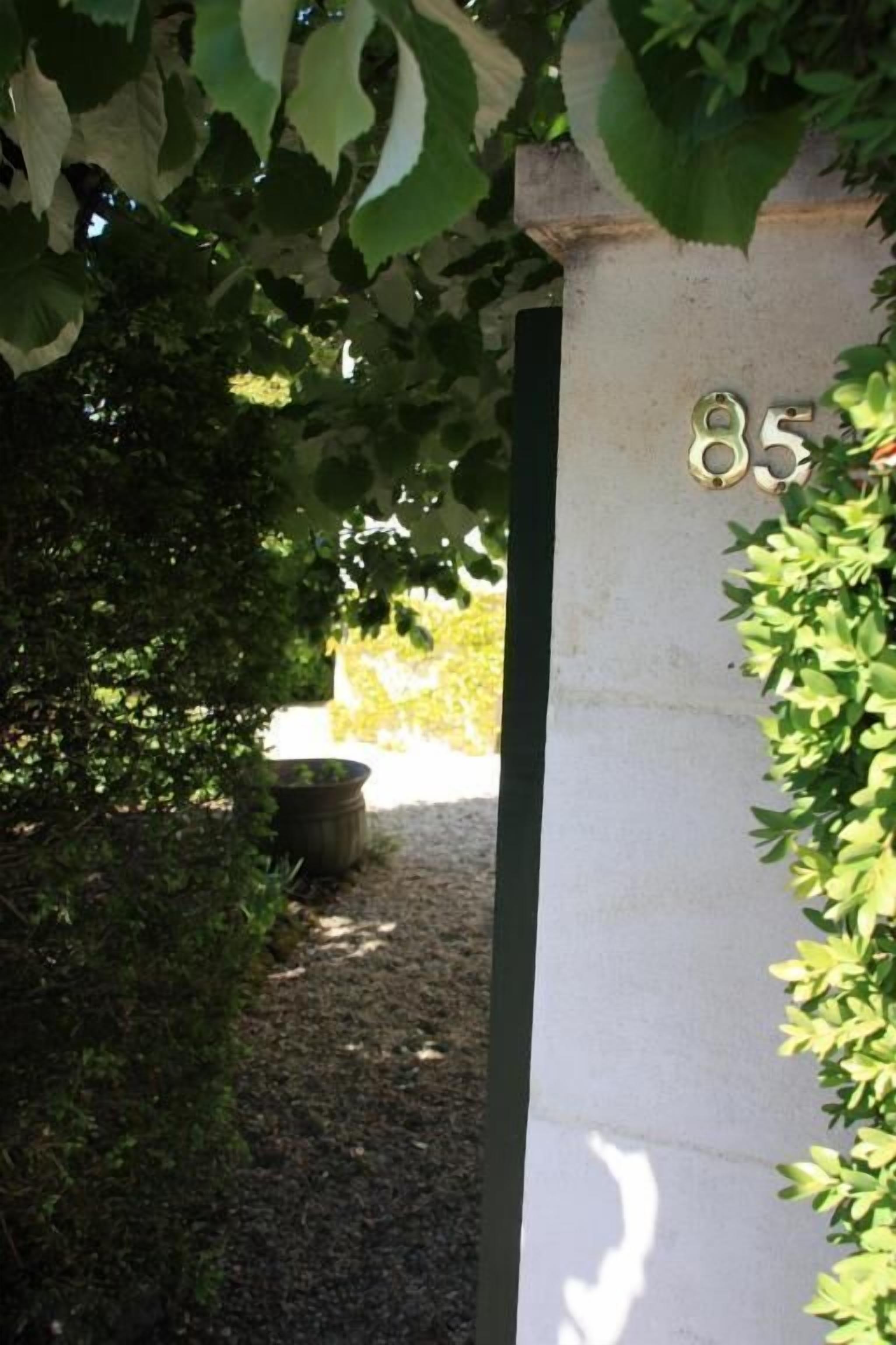 A concrete pillar with the number 85, surrounded by greenery and a gravel path.