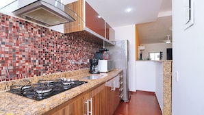 A modern kitchen with a granite countertop, stainless steel appliances, and a red-tiled backsplash.
