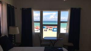 Habitación de hotel con cama, una mesa y vista a la playa.