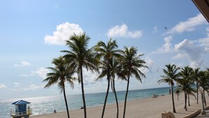 Una playa con palmeras, una torre de salvavidas y cielo despejado.