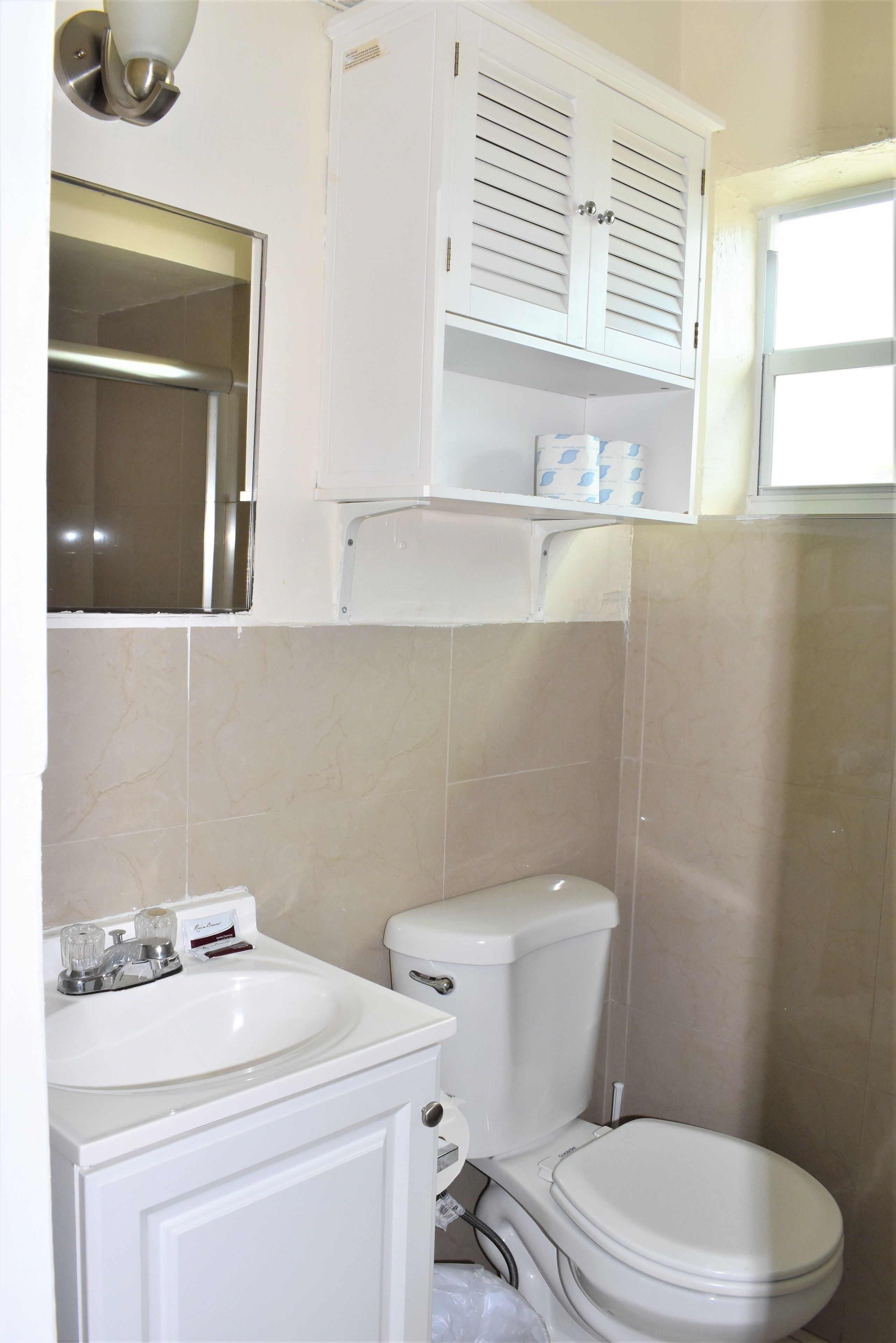 A bathroom with a white sink, toilet, and cabinet.