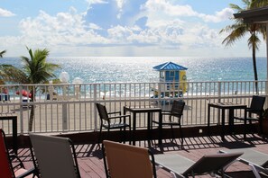 Enjoy the ocean view from this seaside terrace with tables and chairs, surrounded by a safe railing.
