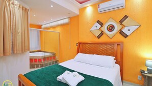 A hotel room with a bed, a green bedspread, a white pillow, a towel, an air conditioning unit, and a wall decoration. - MZapartments Nossa Senhora Penthouse (Rio de Janeiro)
