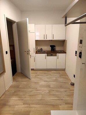 A compact kitchen with white cabinets, a coffee maker, and a sink. - Hotel Blaue Blume (Freiberg)