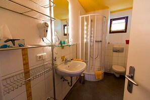 Un baño con lavamanos, cabina de ducha de vidrio, inodoro y espejo.