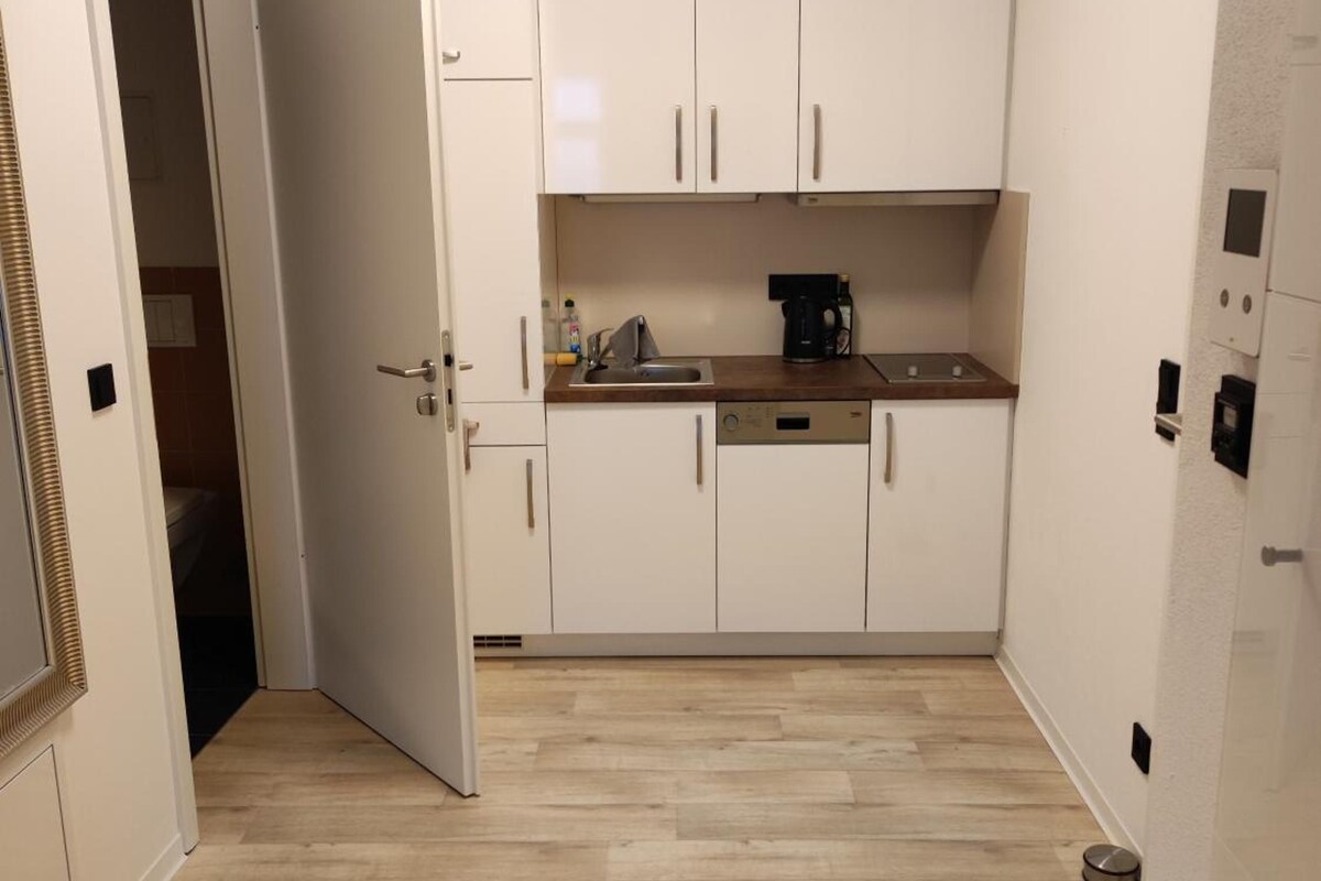 A compact kitchen with white cabinets, a coffee maker, and a small sink.