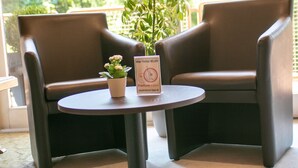 Two brown leather chairs facing each other around a small round table with a potted plant and a sign. - Haus am Wasserfall (Detmold)