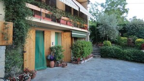 A two-story building with a wooden facade, a green door, and a balcony with potted plants. - L'Ulivo Chiantigiana 115 (Florence)
