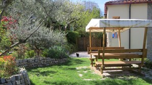 A garden with a wooden bench, a stone wall, and a building with a tiled roof. - L'Ulivo Chiantigiana 115 (Florence)