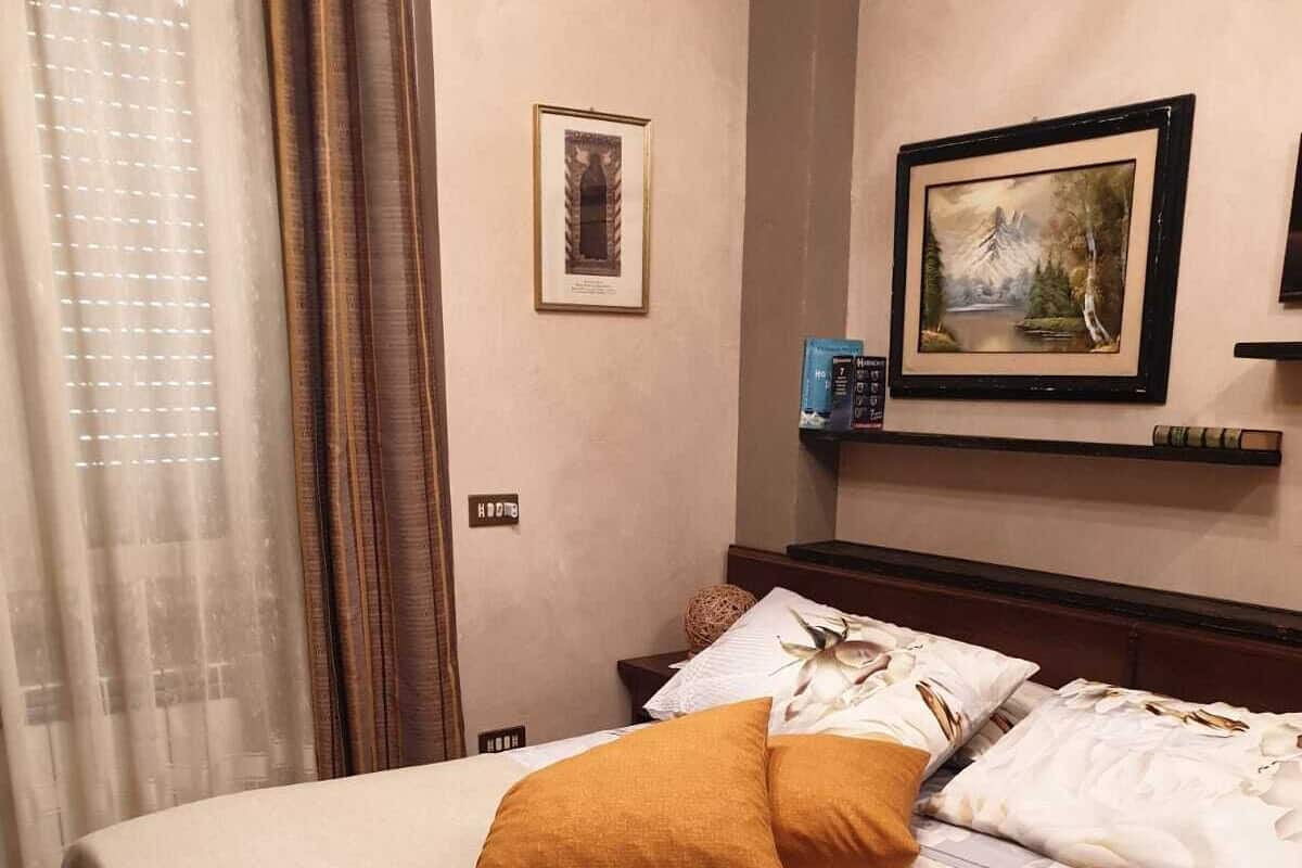 Un lit bien fait, avec une jupe à volants, un tableau encadré au mur et une fenêtre avec des rideaux.