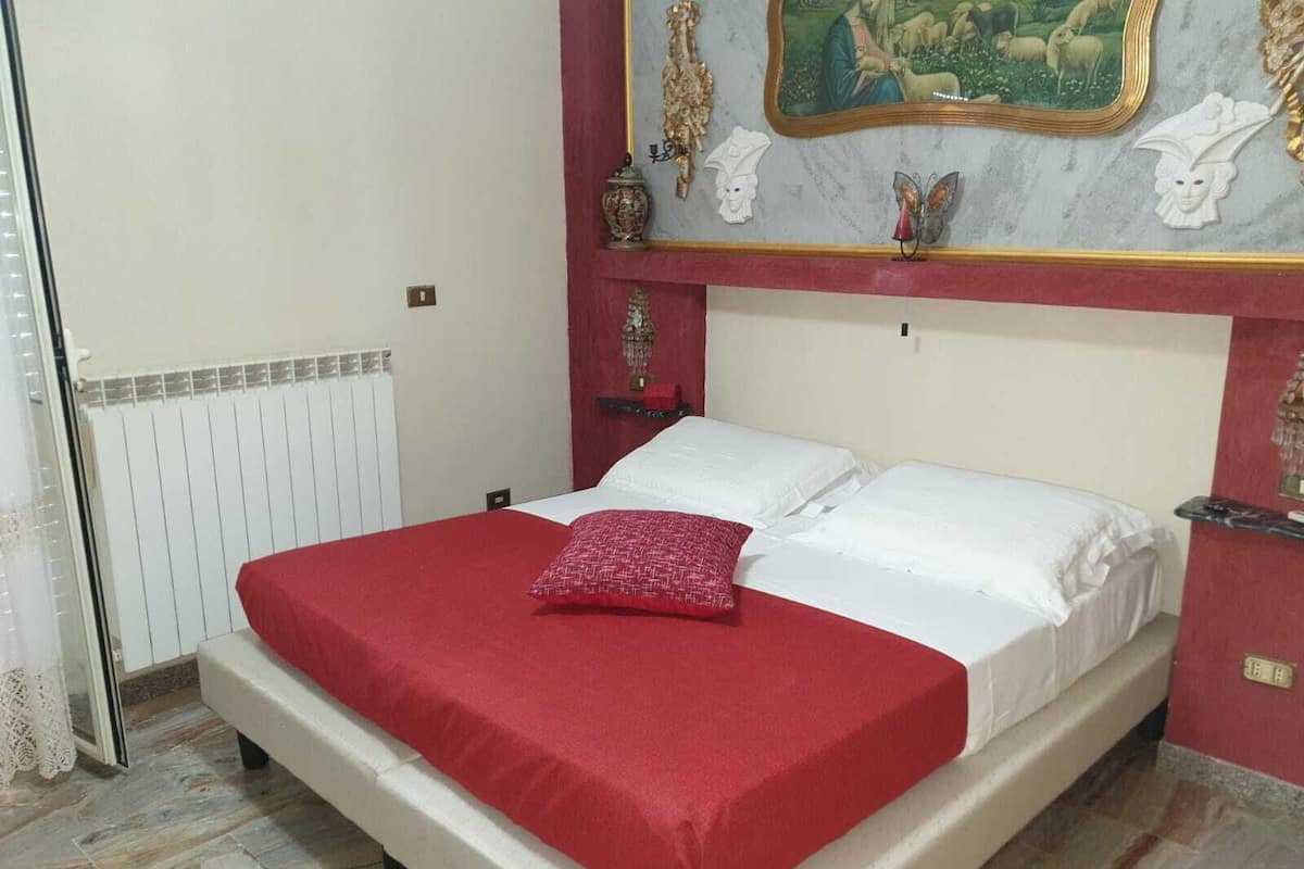 Une chambre à coucher avec un lit, un radiateur, une porte et un mur orné d’un tableau.