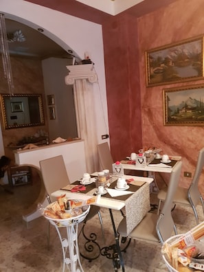 A dining area with tables set for breakfast, including bread, pastries, and coffee cups. - Lussuoso B&B Palazzo Putrino (Palmi)