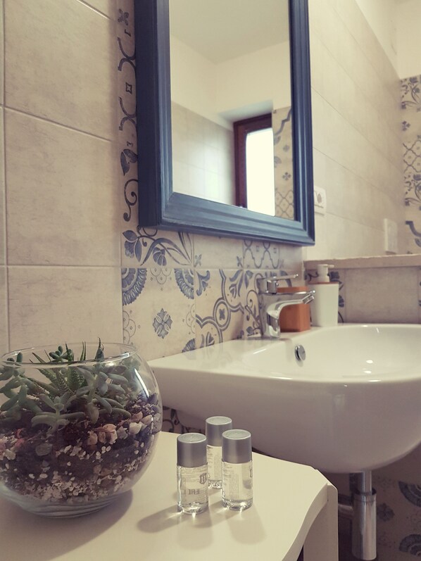 A bathroom with a sink, mirror, and decorative tiles. - Lunalì (Alberobello)